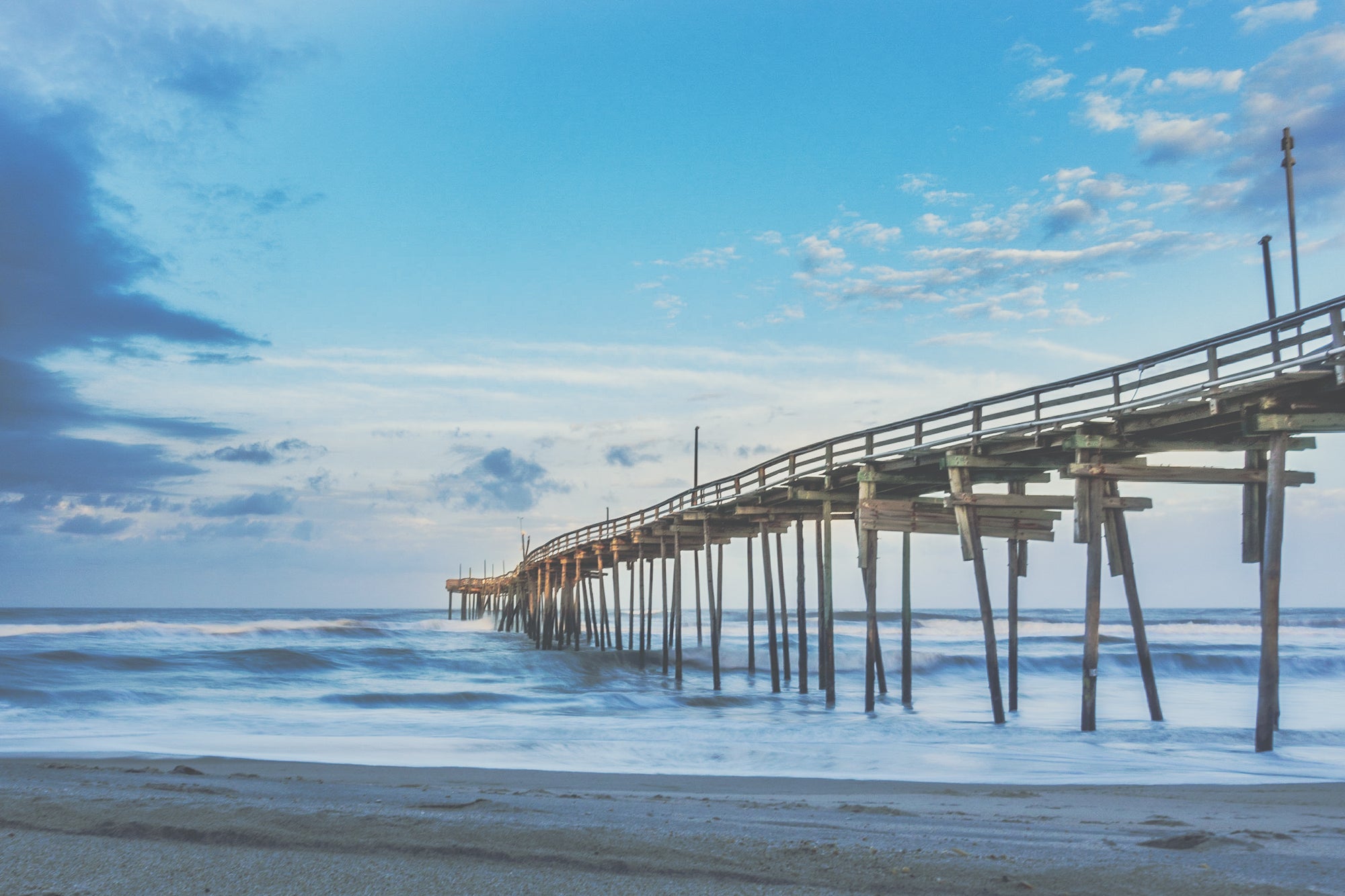 The Avon Fishing Pier during a blue clear sunrise with beautiful clouds and the mystic Atlantic Ocean. 