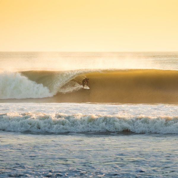 An Outer Bank's surfer enjoying the waves of Avon North Carolina during sunset's golden hour.